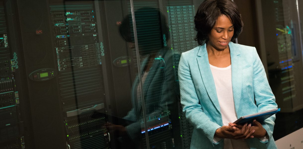 Woman reading tablet in front of giant computer