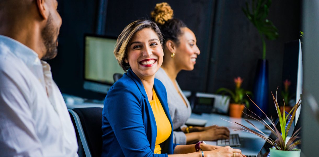 two women and a man sitting with computers