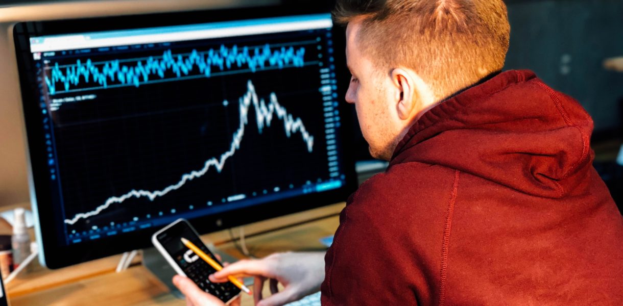Guy using blockchain technology to look at bitcoin on a computer and mobile