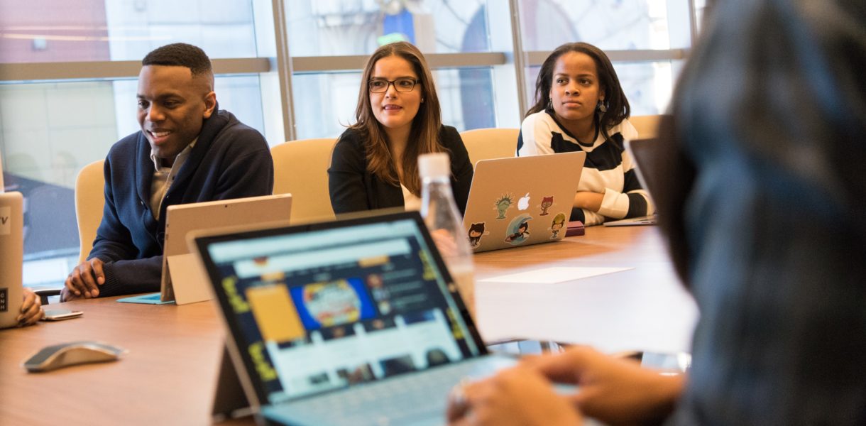 adults sitting at table with computers