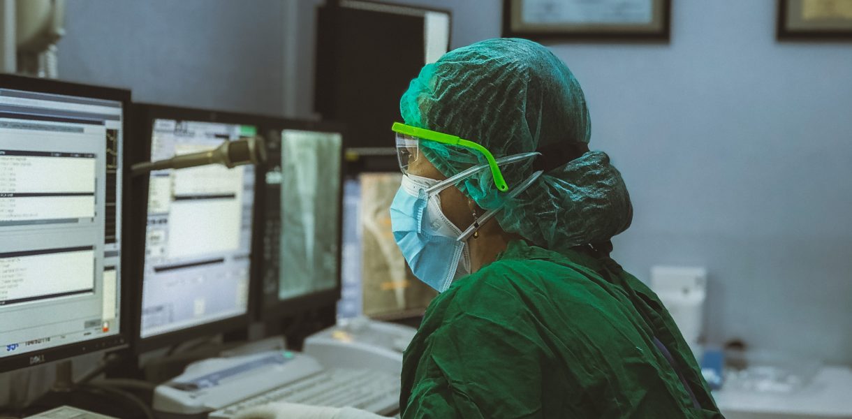 Doctor using computer wearing face covering