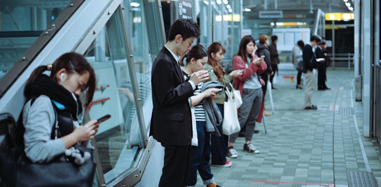 people on train platform on phones