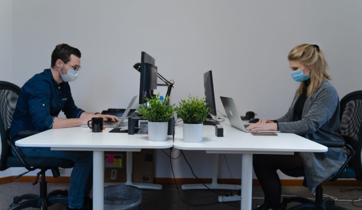 man and woman working in the office with masks on