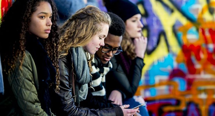 youths sat outside looking at a phone