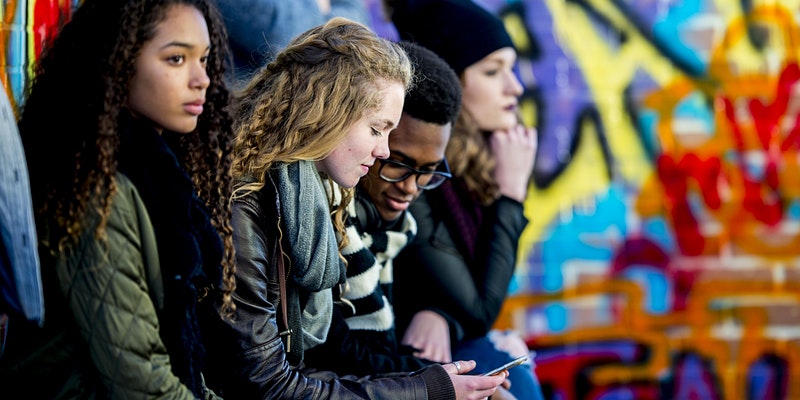 youths sat outside looking at a phone