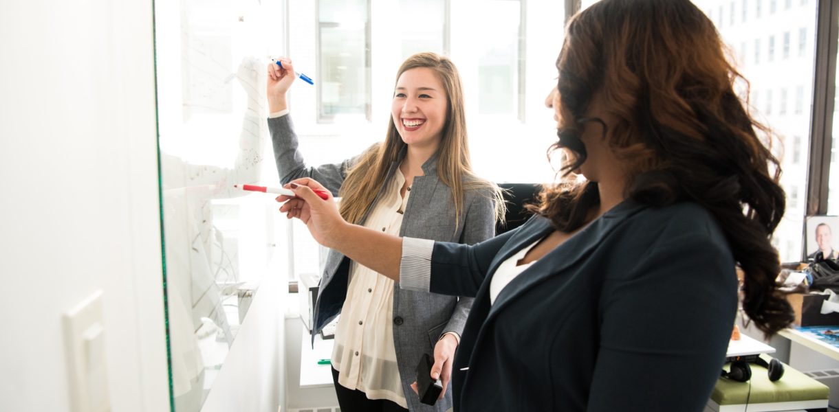 @ Women talking at a white board