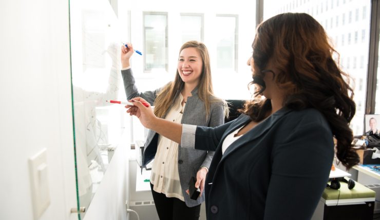 @ Women talking at a white board