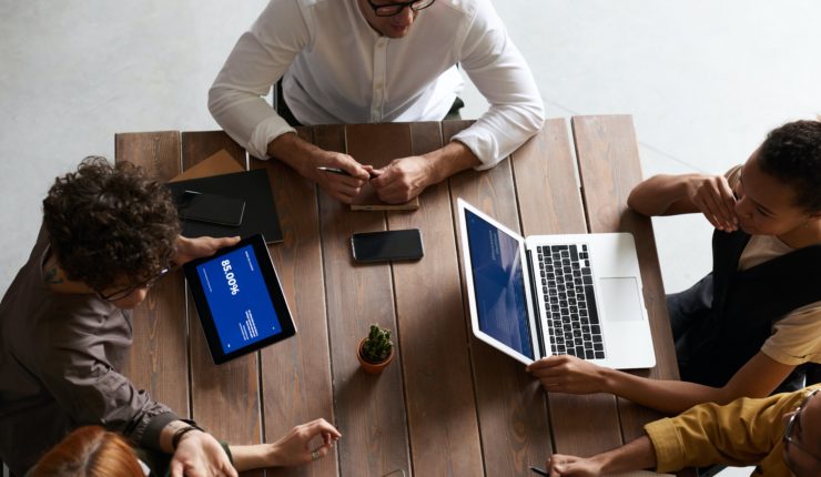 group of people at a table working on laptops