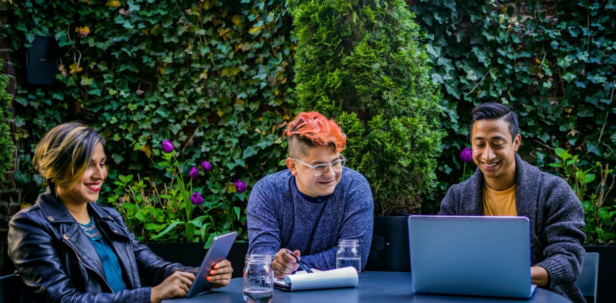 Woman and 2 men working at a table round a laptop