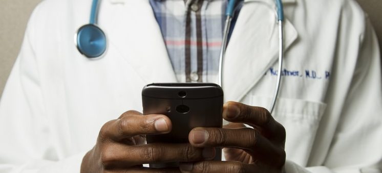doctor typing on phone