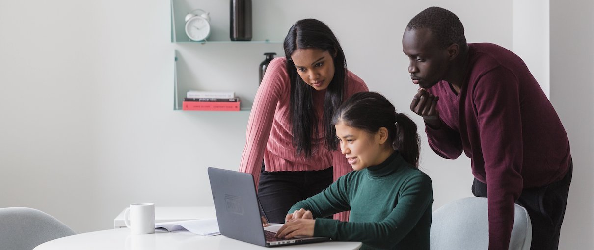 Three people around laptop