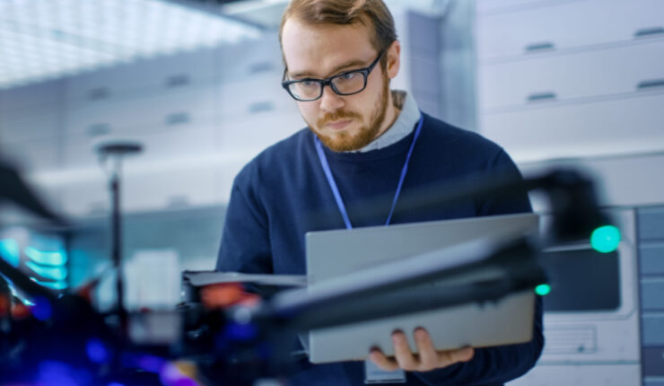 Young,Male,Engineer,Programs,Drone,While,Holding,Laptop,In,His