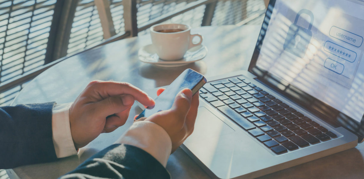 Man using phone to get authentication code for doc on laptop