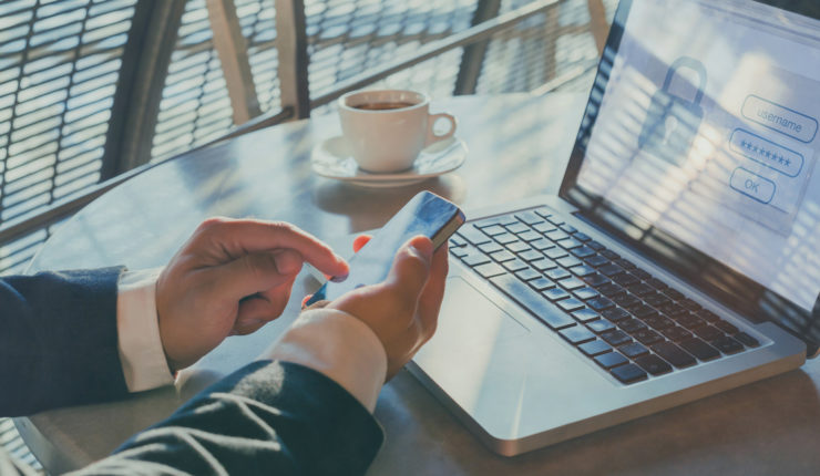 Man using phone to get authentication code for doc on laptop
