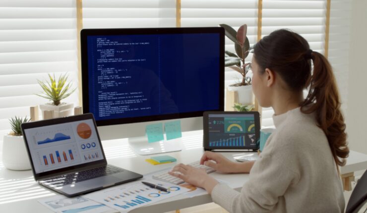 Woman using the computer and 2 other devices sat at a desk