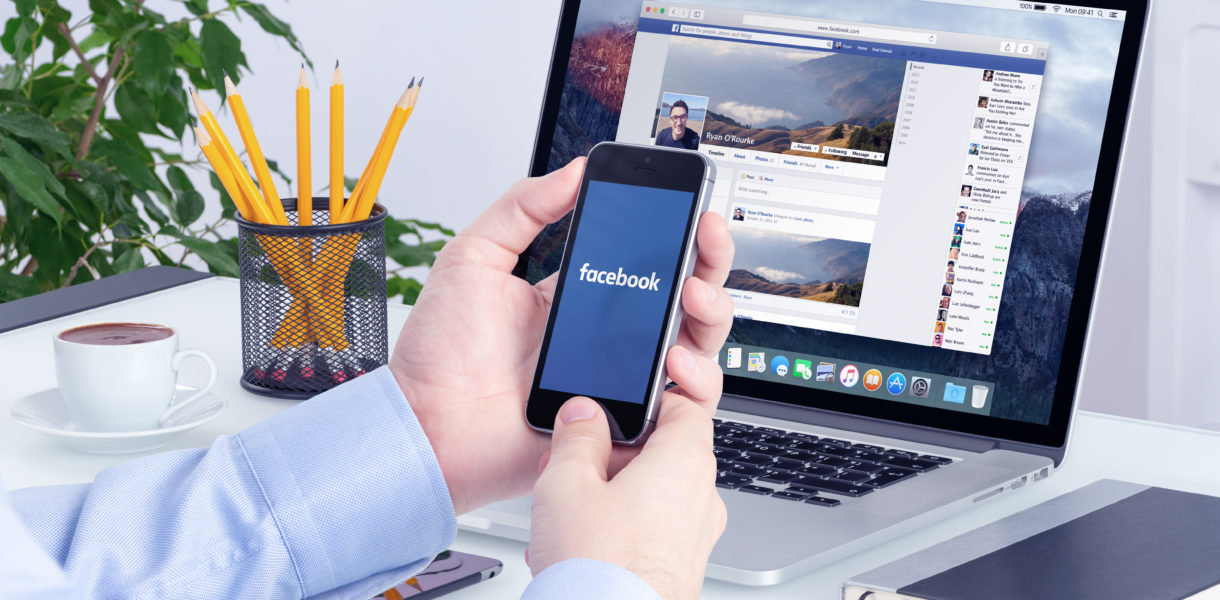 Man using facabook on laptop and phone