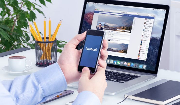 Man using facabook on laptop and phone