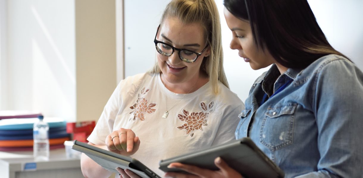 two women looking at tablets